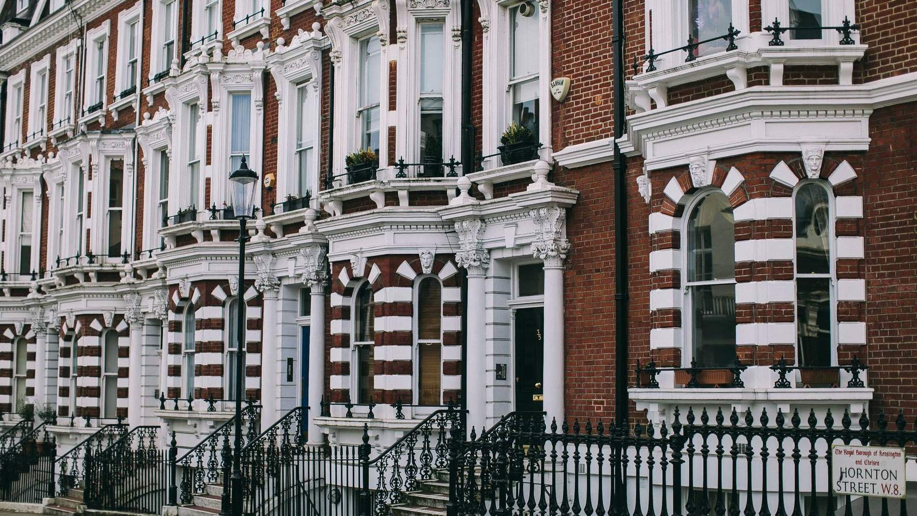 A row of Victorian red-brick and stucco terraced houses on a west London street